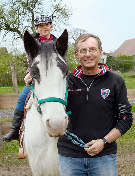 Bernd Siggelkow standing next to a horse a child is sitting on (Photo)